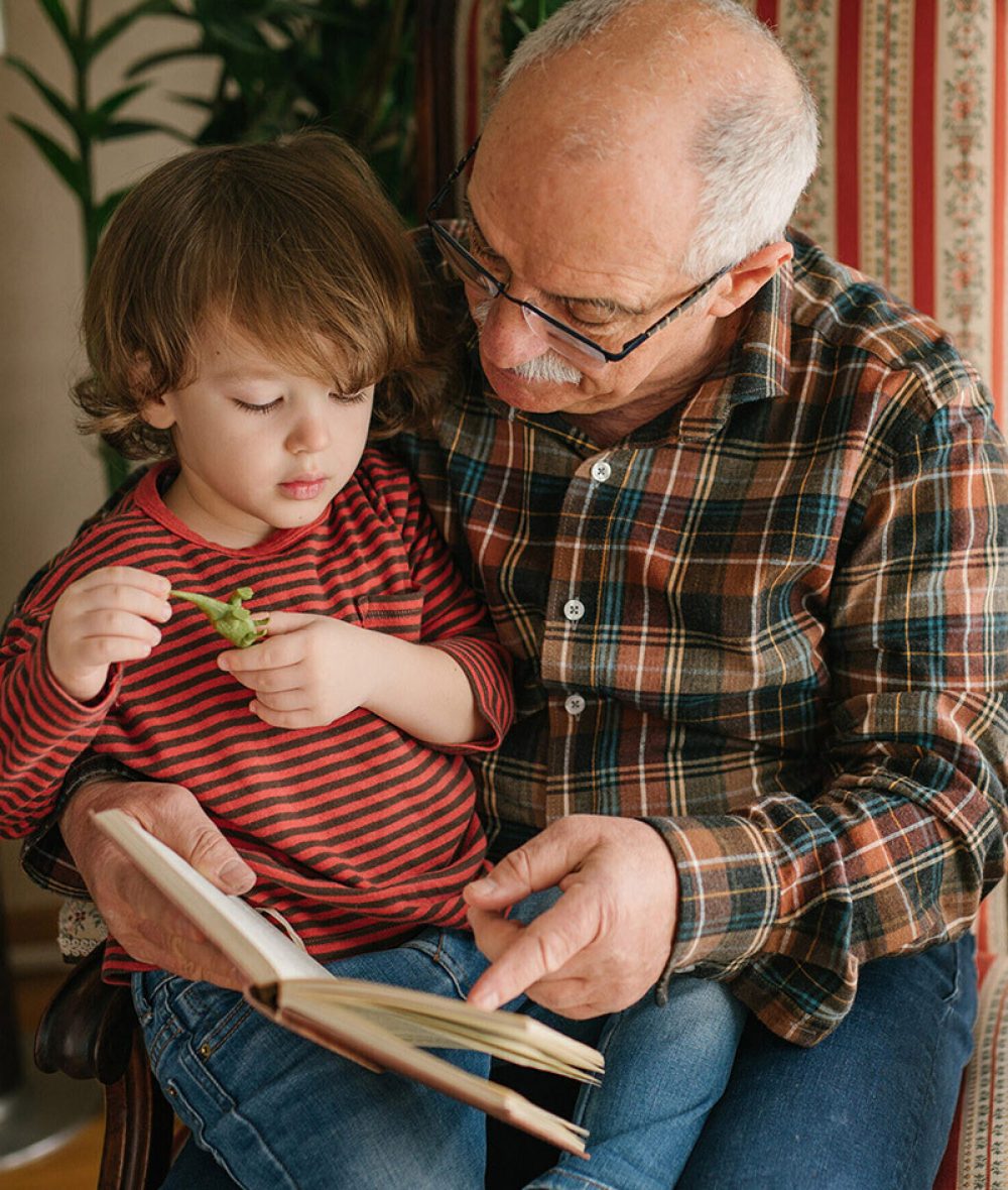 Grossvater liest seinem Enkel ein Buch vor, das es ihm geschenkt hat