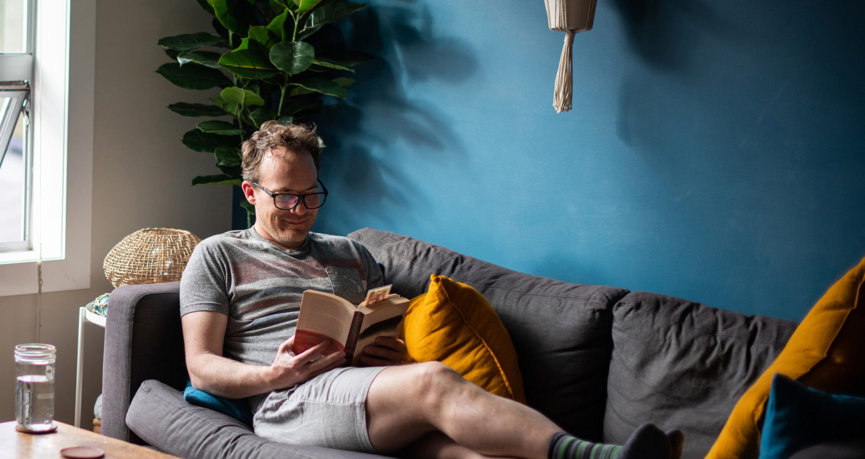 Man liest auf dem Sofa ein Buch, das er geschenkt bekommen hat.